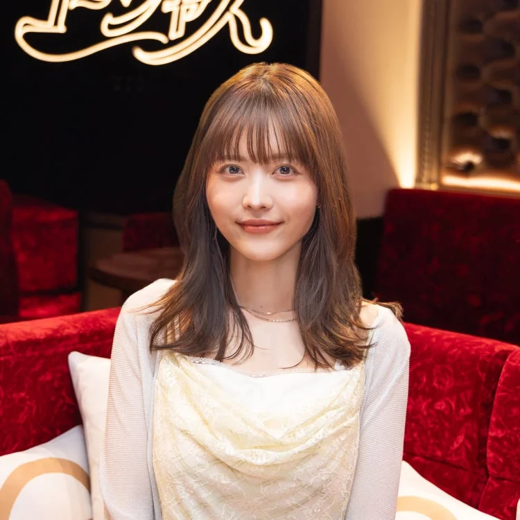 赤いソファに座って優しく微笑む新田さちかさん
