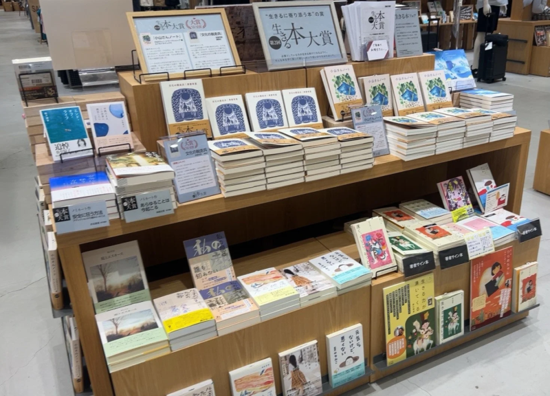 書店内の書籍陳列棚で、多数の本が並べられています。「本大賞」や「生きるに寄り添う本」のフェアが開催されており、受賞作やおすすめの書籍が前面にディスプレイされています