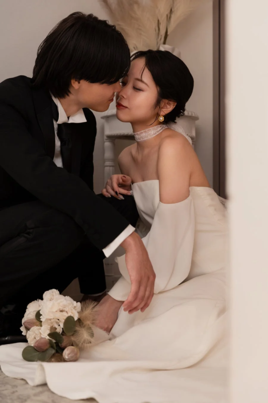 結婚式の衣装を身につけたカップルが、顔を近づけて見つめ合っているロマンチックな瞬間を捉えた画像です。