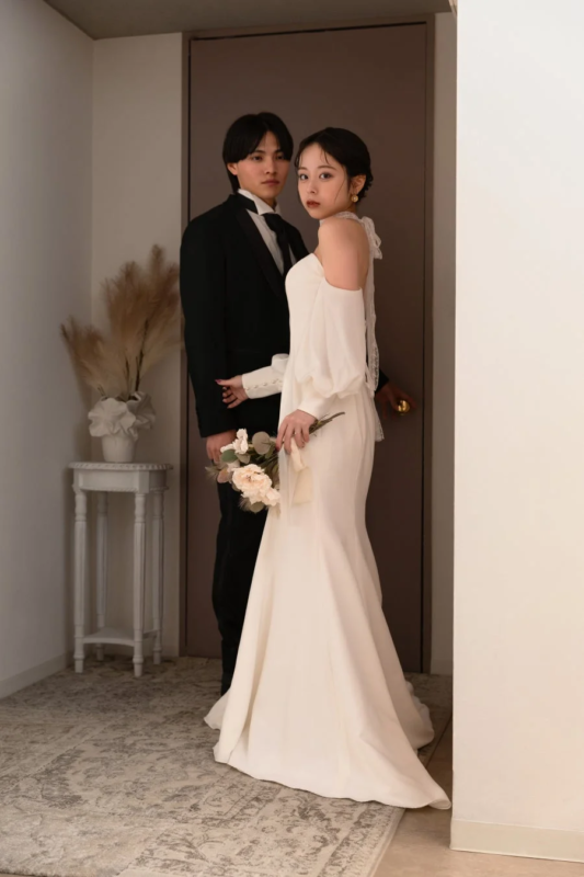 結婚衣装をまとった新郎新婦がカメラ目線で立つポートレート写真です。