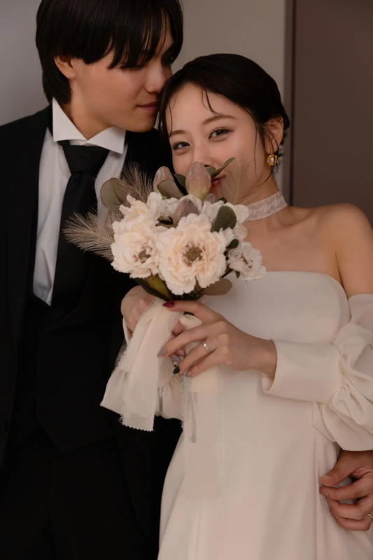 ウェディングドレス姿の花嫁とタキシード姿の花婿が寄り添うロマンチックなポートレート写真です。