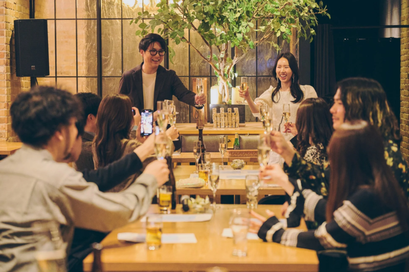 レストランで大勢の人が集まり、シャンパンで乾杯している楽しそうな様子