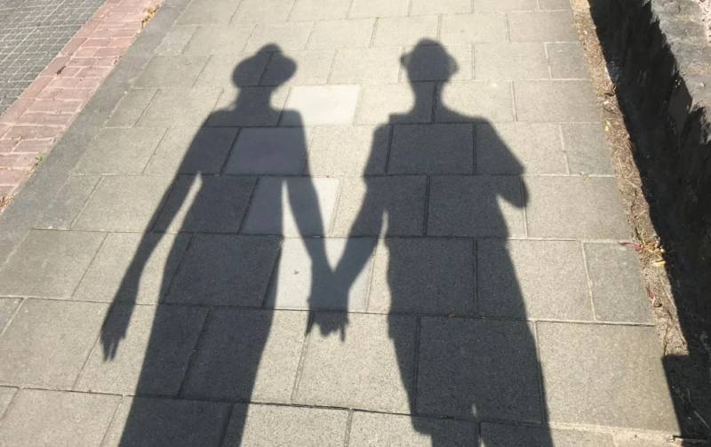 手をつないで歩くカップルの影